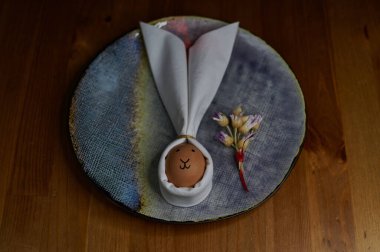 Tabakta bir buket kurutulmuş çiçekle peçete ve yumurta tavşanı.