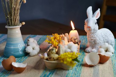 Yumurta kutusunda yanan mumlar, tavşan ve mimozayla dekore edilmiş.