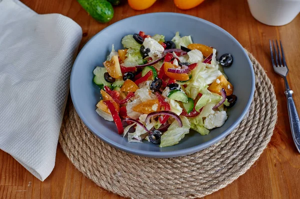 Çatal ve jütten yapılmış peçeteyle ahşap arka planda Yunan salatası