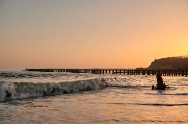 Kıyıdaki Karadeniz 'deki ağaç kütüğü rıhtımın arka planına ve akşamları günbatımına karşı