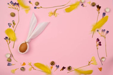 Yumurta tavşanı açık pembe arka planda paskalya tüyleri, kurutulmuş çiçekler ve yumurta kabukları içeren yazı için.