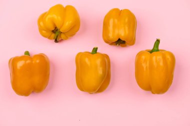 Açık pembe arka planda birkaç biber yatay olarak yakın plan