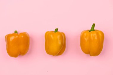 Açık pembe arka planda sarı biber yatay olarak yakın plan