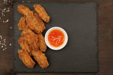 Tavuk kanatları, kırmızı acı soslu ekmeklenmiş fast food. Yatay bir tabakta.