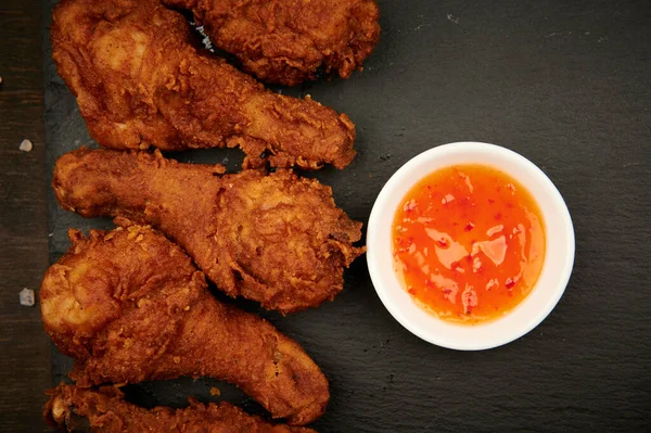 Ekmekli fast food ve kırmızı soslu tavuk budu yatay tabakta yakın plan.