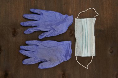 Hijyenik koruyucu malzeme, eldivenler ve maske, koyu ahşap arka planda güvenlik.