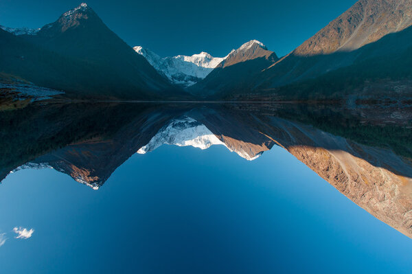 White Mountains are reflected in smooth water. Gorny Altai Russia