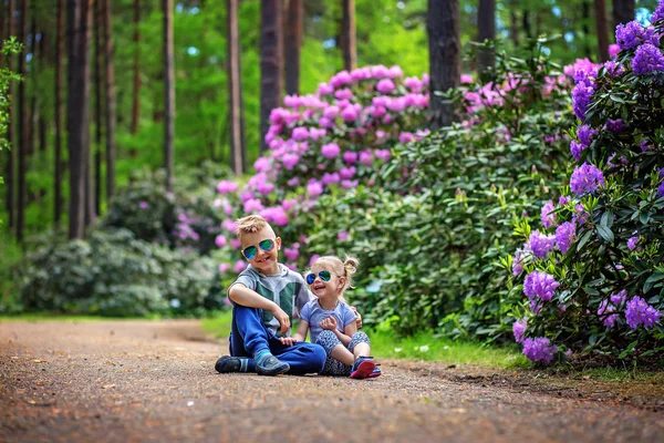 Portrait von entzückenden Geschwistern, die zusammen lächeln und lachen, während sie draußen sitzen. happy lifestyle kids.author Behandlung: zusätzliches Rauschen, weicher Fokus, Farbkorrektur. — Stockfoto