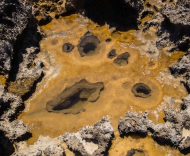Deniz kıyısındaki arkaplan ve dokular su dolu taş birikintileri ve zamanda donmuş deniz tuzu kalıntıları.