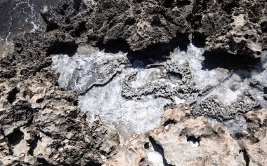 Deniz kıyısı, deniz suyu formunda tuz desenleri ve deniz lagünlerinin oluşumuyla güneşin gölgeleriyle birlikte suyun altında dokular ve taş soyutlamalarıyla doludur.