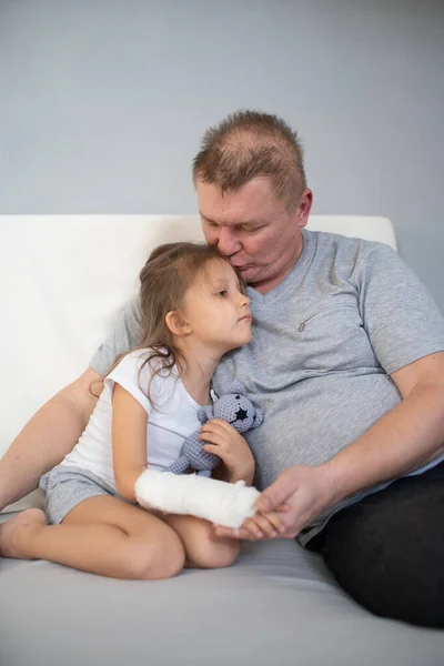 Dad pities daughter with a sore arm in a cast? gypsum on the arm child