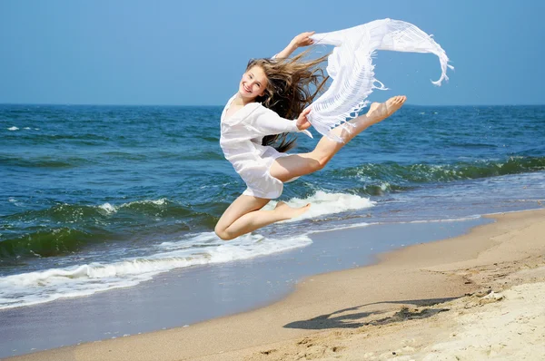 Happy young girl jumping on the beach — Stock Photo, Image