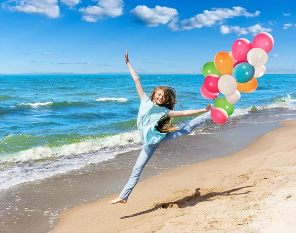 Happy girl runningg on the beach with balloons — Stock Photo, Image