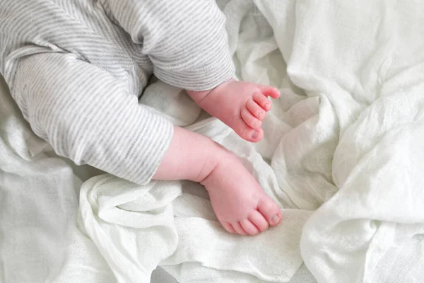 Close up of newborn legs on a white blanket, childhood and maternity concept. Baby feet. Selective focus. Horizontal