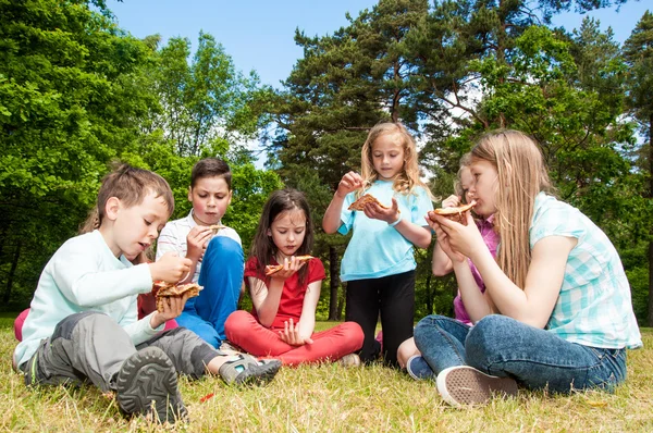 Grupo de niños comiendo pizza — Foto de Stock