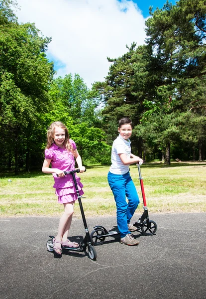 男孩和女孩在滑板车上 — 图库照片