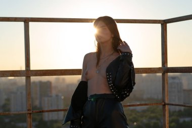 Genç ve güzel bir kadın dışarıda çıplak poz veriyor.