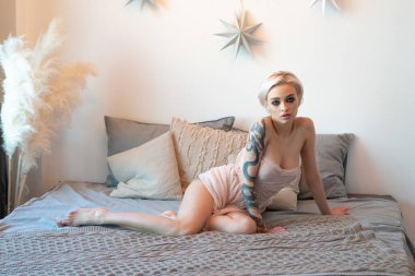 Genç ve güzel bir kadın iç çamaşırlarıyla yatakta oturuyor.