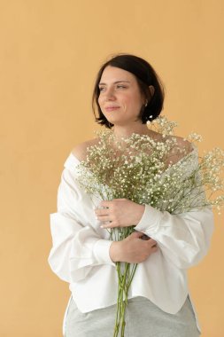 Stüdyoda, sarı arka planda beyaz çiçekli güzel bir kadının portresi.