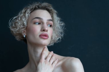 Stüdyoda beyaz kıvırcık saçlı bir kızın portresi.