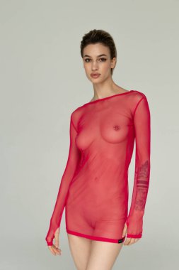 Genç ve güzel bir kadın stüdyoda kırmızı iç çamaşırlarıyla poz veriyor.