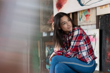 Stüdyoda ekose gömlekle poz veren genç ve güzel bir kadın.