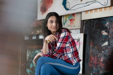 Stüdyoda ekose gömlekle poz veren genç ve güzel bir kadın.