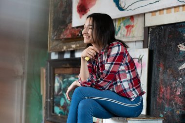 Stüdyoda ekose gömlekle poz veren genç ve güzel bir kadın.