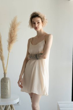 Genç ve güzel bir kadın stüdyoda beyaz iç çamaşırlarıyla poz veriyor.