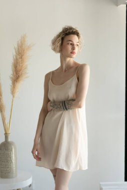 Genç ve güzel bir kadın stüdyoda beyaz iç çamaşırlarıyla poz veriyor.