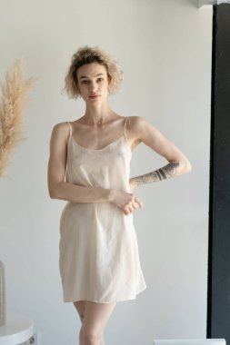 Genç ve güzel bir kadın stüdyoda beyaz iç çamaşırlarıyla poz veriyor.