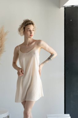 Genç ve güzel bir kadın stüdyoda beyaz iç çamaşırlarıyla poz veriyor.