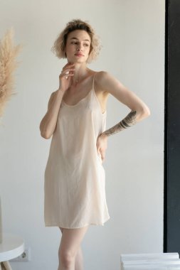 Genç ve güzel bir kadın stüdyoda beyaz iç çamaşırlarıyla poz veriyor.