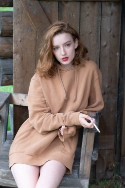 Taşralı kadın elinde sigarayla ahırın yanında oturuyor.