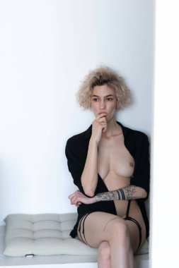 Genç ve güzel bir kadın stüdyoda oturup sigara içiyor.