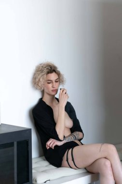 Genç ve güzel bir kadın stüdyoda sigara içiyor.