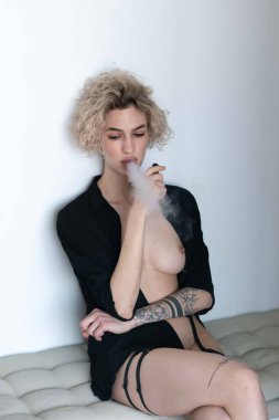 Genç ve güzel bir kadın stüdyoda sigara içiyor.