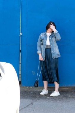 Dışarıda mavi kot ceketli güzel bir kadın poz veriyor.