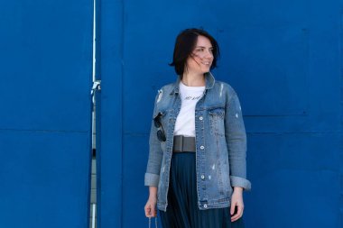 Dışarıda mavi kot ceketli güzel bir kadın poz veriyor.