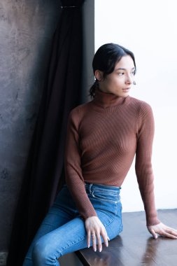 Stüdyoda süveter ve kot pantolon giymiş güzel bir kadın.