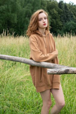 Yazın kahverengi bir kazakla tarlada poz veren güzel bir kadın.