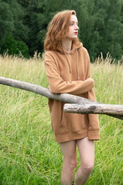 Yazın kahverengi bir kazakla tarlada poz veren güzel bir kadın.
