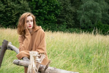 Yazın kahverengi bir kazakla tarlada poz veren güzel bir kadın.