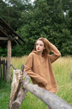 Yazın kahverengi bir kazakla tarlada poz veren güzel bir kadın.