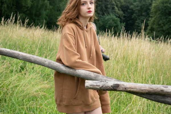 Yazın kahverengi bir kazakla tarlada poz veren güzel bir kadın.