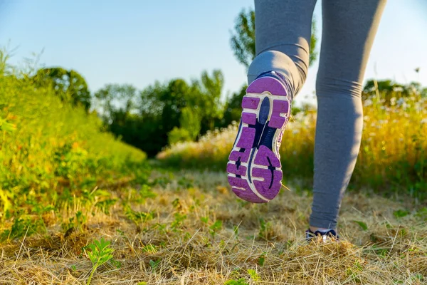 Donna che corre al tramonto in un campo — Foto Stock