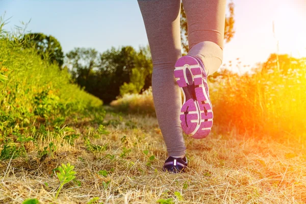 Donna che corre al tramonto in un campo — Foto Stock