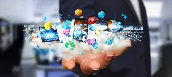 Businessman holding tech devices and icons applications over a c