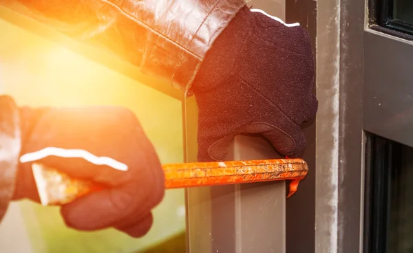 Burglar wearing leather coat breaking in a house — Stock Photo, Image