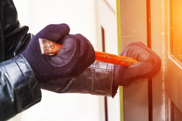 Burglar wearing leather coat breaking in a house — Stock Photo, Image